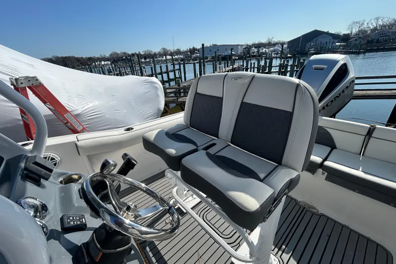 Slide: The Image of 2020 Tidewater 232 LXF boat interior with dual seats and steering wheel, docked by the water. - 12