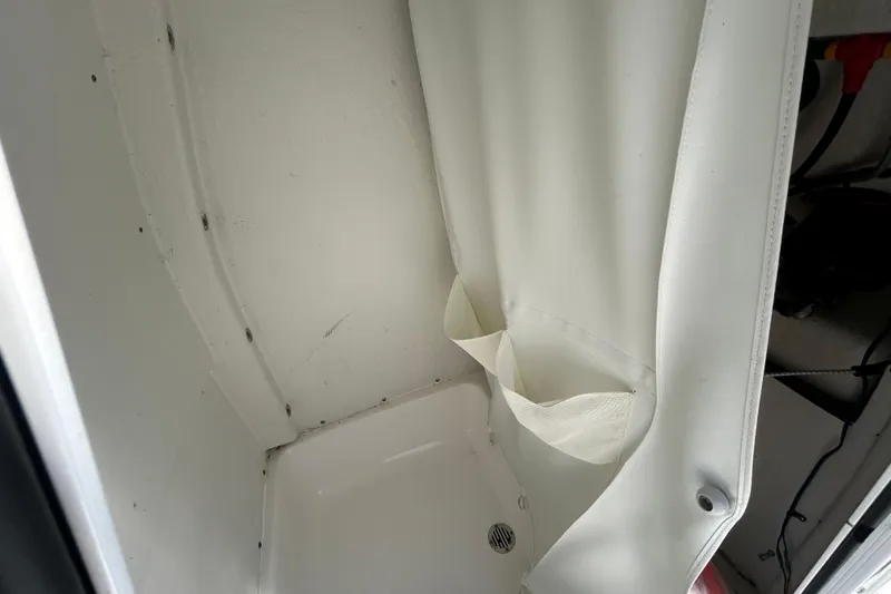 Slide: The Image of 2020 Tidewater 232 LXF boat interior with white shower area and curtain. - 15