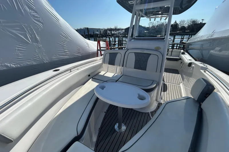 Slide: The Image of 2020 Tidewater 232 LXF boat interior with seating and table, docked outdoors. - 19