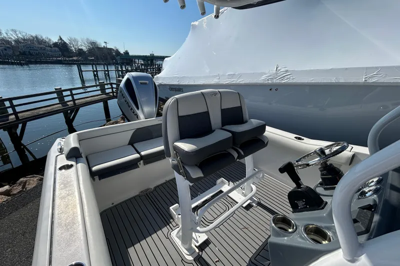 Slide: The Image of 2020 Tidewater 232 LXF boat interior with dual seats and steering, docked by the water. - 2