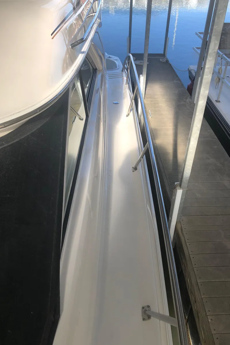 Slide: The Image of 2001 Sea Ray 400 Sedan Bridge yacht docked, side view with railing and water reflection. - 16