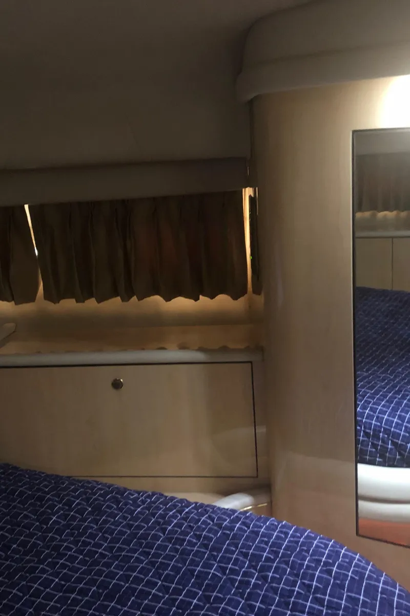 Slide: The Image of Interior cabin of 2001 Sea Ray 400 Sedan Bridge with blue bedding and wooden cabinetry. - 39