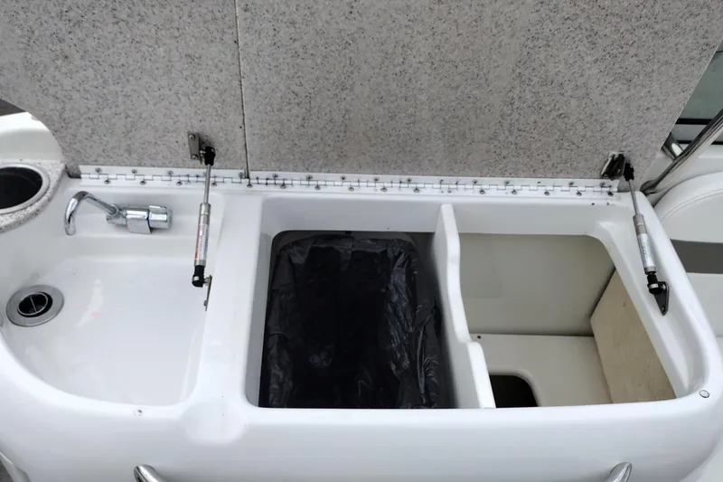 Slide: The Image of Open storage compartment on a 2004 Formula 260 Bowrider boat, featuring a sink and faucet. - 15