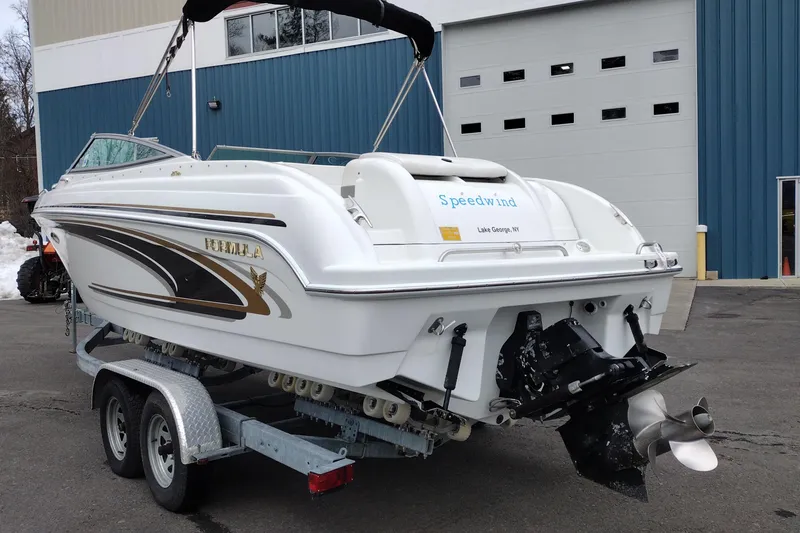 Slide: The Image of 2004 Formula 260 Bowrider boat on trailer, parked outside a blue building. - 6