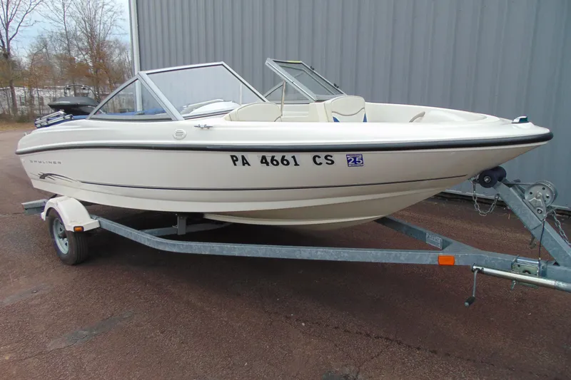 The Image of 2004 Bayliner 1750 Capri boat on trailer, parked outdoors near a building. - 1