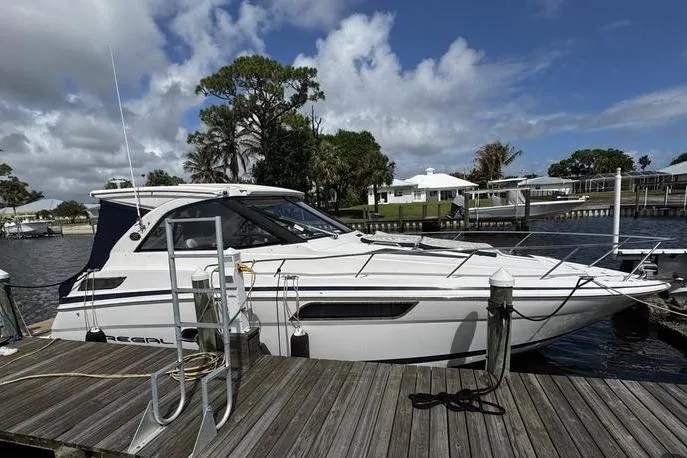 The Image of 2018 Regal 35 Sport Coupe docked at a marina under a partly cloudy sky. - 1