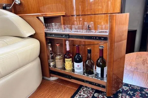Slide: The Image of Bar cabinet in 2003 Viking Princess 50 Sport Cruiser with assorted bottles and glasses. - 28