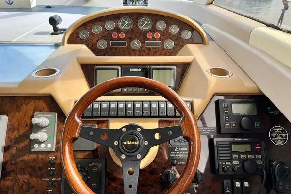 Slide: The Image of 2003 Viking Princess 50 Sport Cruiser helm with wood steering wheel and control panel. - 33