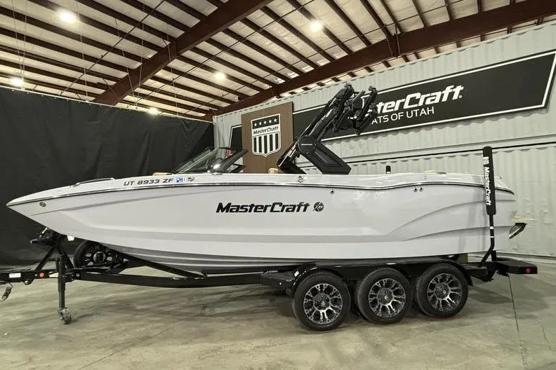 Slide: The Image of 2024 MasterCraft X24 boat in showroom, side view with trailer. - 2