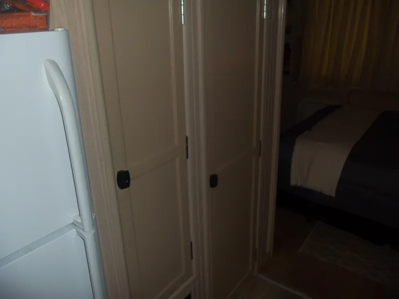 Slide: The Image of Hallway with white refrigerator, wooden doors, and a glimpse of a bedroom. - 36
