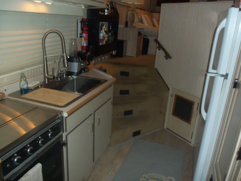 Slide: The Image of Compact kitchen area in a 2003 Gibson Classic boat, featuring a sink, stove, and stairs. - 42