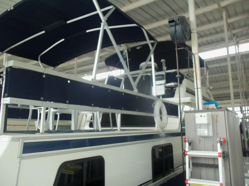 Slide: The Image of 2003 Gibson Classic boat with blue canopy and white railing in a covered dock. - 5