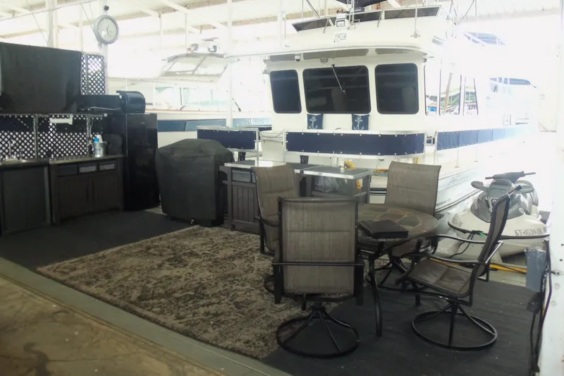 Slide: The Image of Outdoor seating area with chairs and table beside a 2003 Gibson Classic boat in a marina. - 9