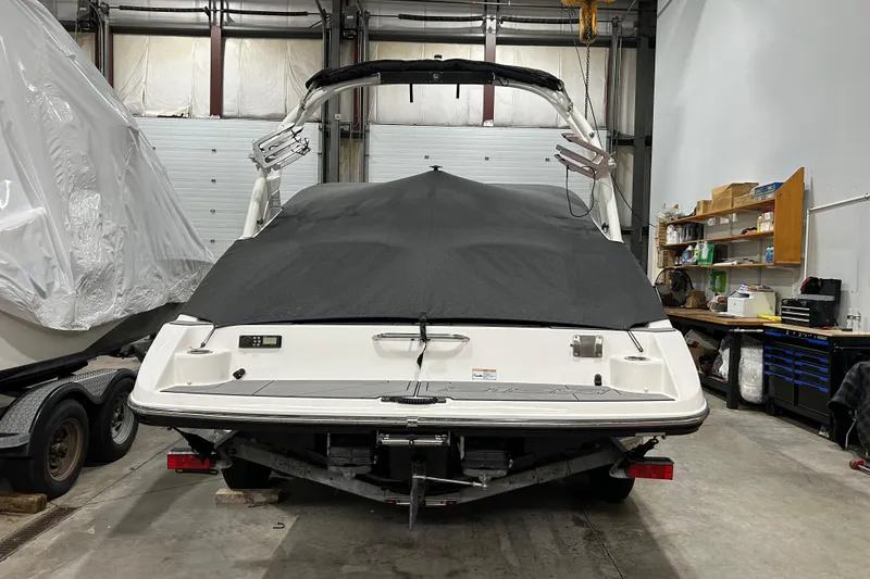 Slide: The Image of 2019 Yamaha Boats 212X in storage, covered, with trailer in a garage setting. - 8