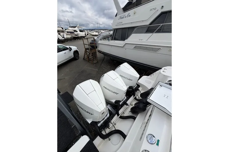 Slide: The Image of 2010 Boston Whaler 345 Conquest with triple outboard engines, docked under cloudy skies. - 11