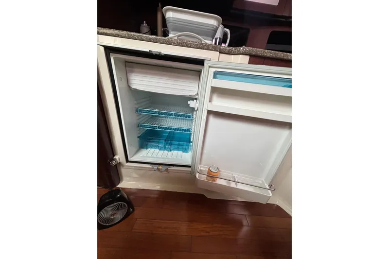 Slide: The Image of Open refrigerator inside a 2010 Boston Whaler 345 Conquest boat, showing shelves and a can. - 54