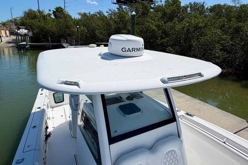 Slide: The Image of 2021 Sportsman Open 302 Center Console boat with Garmin radar, docked near lush greenery. - 16