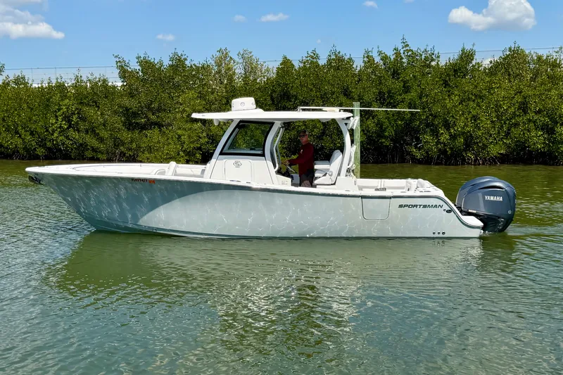 Slide: The Image of 2021 Sportsman Open 302 Center Console boat on calm water, surrounded by greenery. - 3