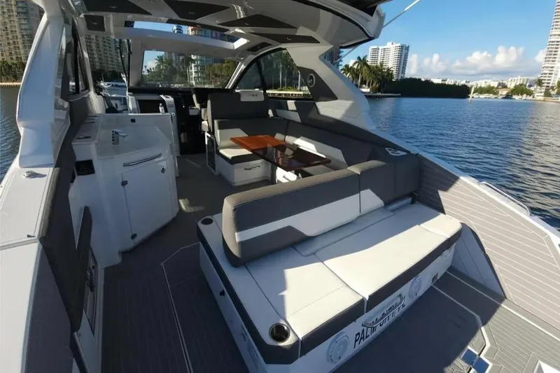 Slide: The Image of 2021 Cruisers Yachts 42 GLS OB interior with seating and table, docked by waterfront. - 12