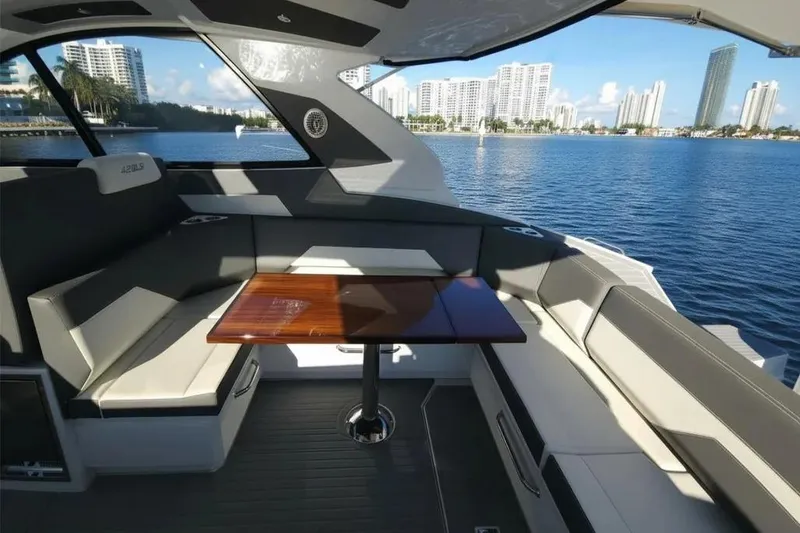 Slide: The Image of 2021 Cruisers Yachts 42 GLS OB interior with seating and table, overlooking waterfront cityscape. - 14