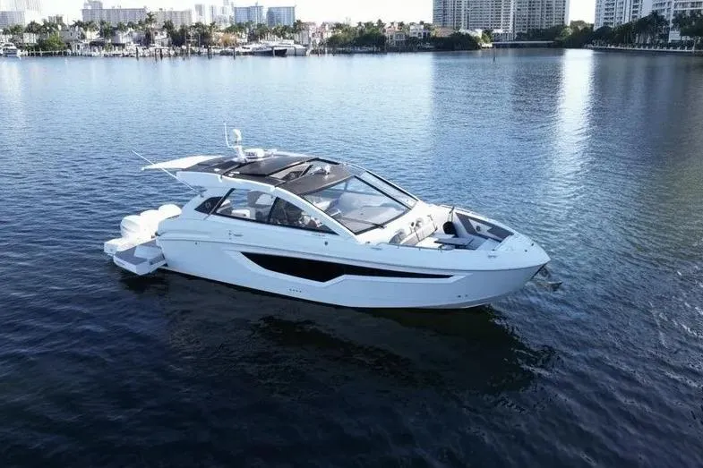 Slide: The Image of 2021 Cruisers Yachts 42 GLS OB on calm water, cityscape background. - 3