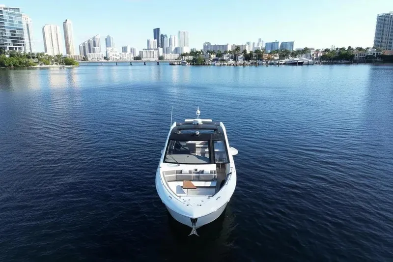 Slide: The Image of 2021 Cruisers Yachts 42 GLS OB on calm water with city skyline backdrop. - 4
