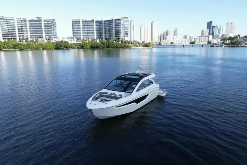 Slide: The Image of 2021 Cruisers Yachts 42 GLS OB on calm water with city skyline backdrop. - 5