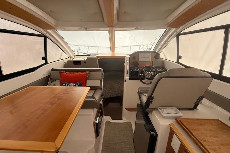 Slide: The Image of Interior of 2022 Cutwater C-24 Coupe boat with helm, seating, and wooden table. - 30