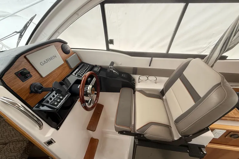 Slide: The Image of 2022 Cutwater C-24 Coupe helm with Garmin navigation, wood accents, and cushioned seating. - 31