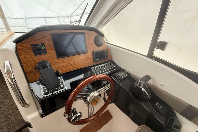 Slide: The Image of 2022 Cutwater C-24 Coupe helm with wood accents, steering wheel, and navigation controls. - 33
