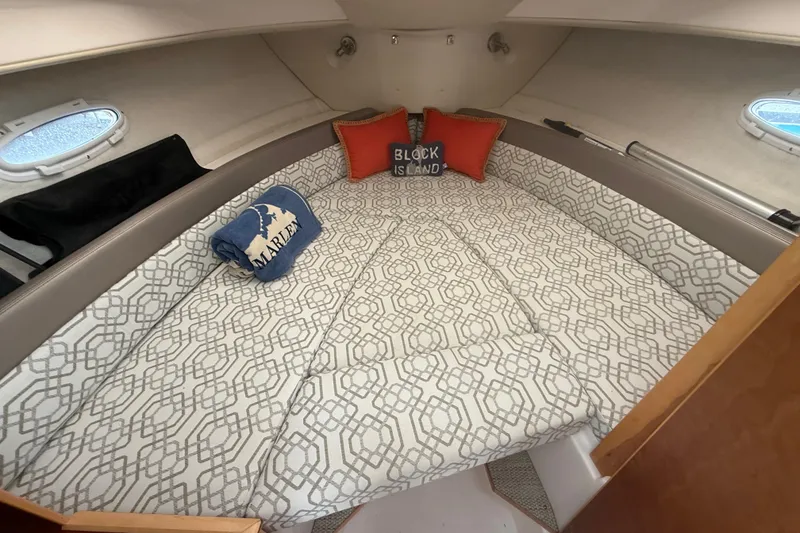 Slide: The Image of 2022 Cutwater C-24 Coupe cabin with patterned bedding and decorative pillows. - 48