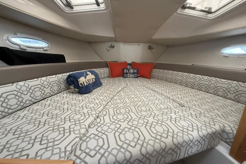 Slide: The Image of 2022 Cutwater C-24 Coupe cabin with patterned bedding and decorative pillows. - 49