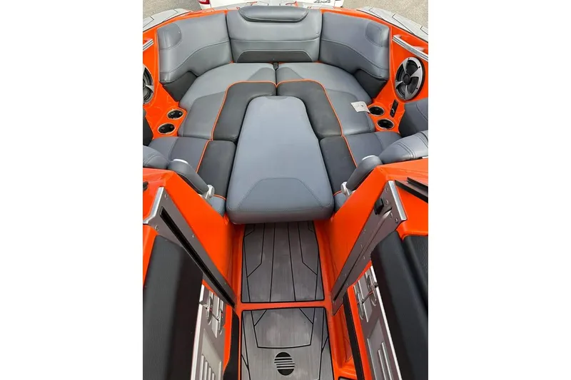 Slide: The Image of 2017 Malibu M235 boat interior with orange and gray seating, cup holders, and speakers. - 10