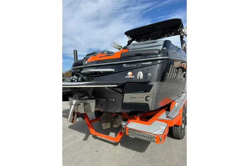 Slide: The Image of 2017 Malibu M235 boat rear view with vibrant orange accents and Surf Gate technology. - 2