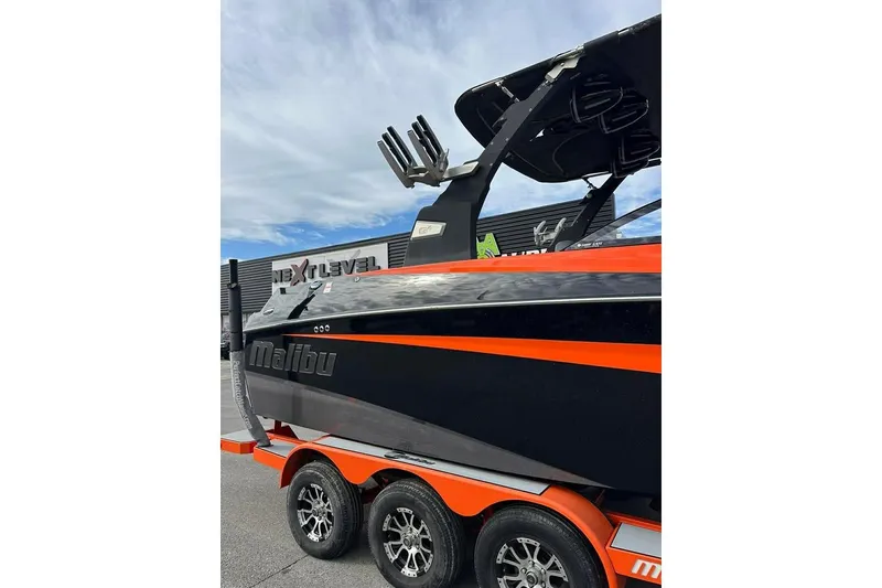 Slide: The Image of 2017 Malibu M235 boat with orange and black design on a trailer. - 3