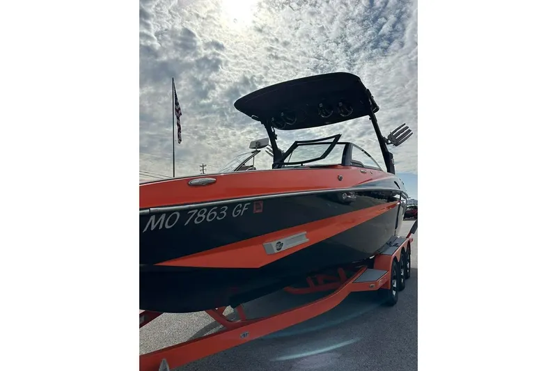 Slide: The Image of 2017 Malibu M235 boat with orange and black design under cloudy sky. - 4