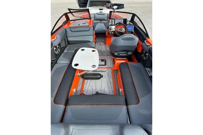 Slide: The Image of 2017 Malibu M235 boat interior with gray and orange seating, steering wheel, and dashboard. - 9