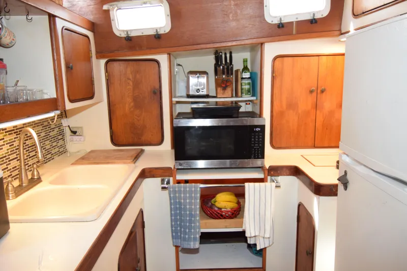 Slide: The Image of 1979 Gulfstar 44 yacht kitchen with wooden cabinets, microwave, and modern appliances. - 30