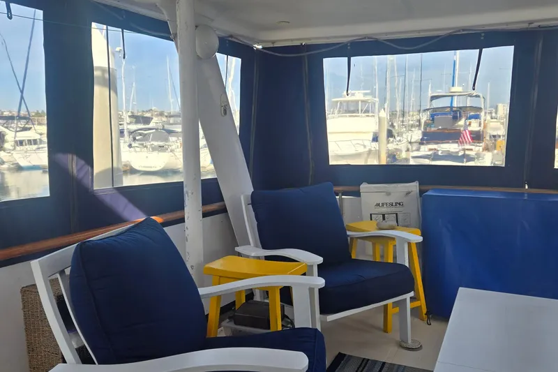 Slide: The Image of Interior of a 1979 Gulfstar 44 yacht with blue cushioned seating and marina view. - 32