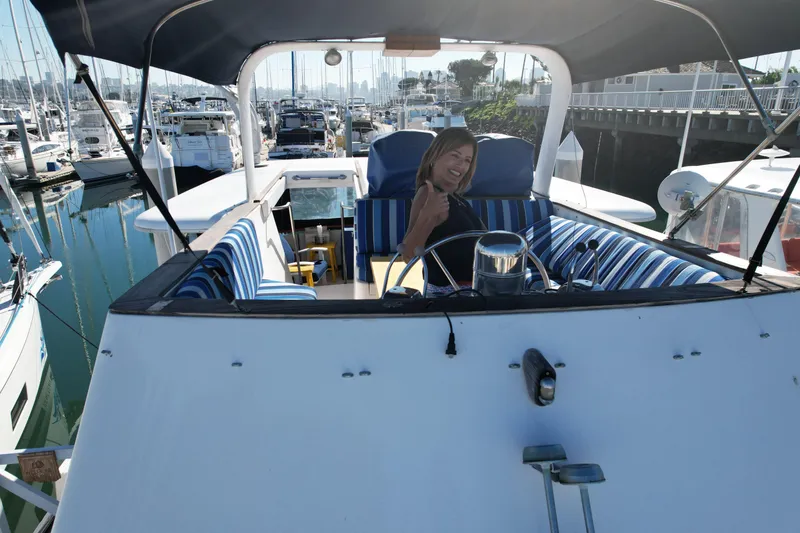 Slide: The Image of 1979 Gulfstar 44 yacht with striped seating, docked in a marina, person smiling at helm. - 42