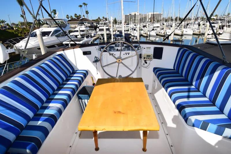 Slide: The Image of Cockpit of 1979 Gulfstar 44 yacht with striped seating and wooden table in marina. - 5