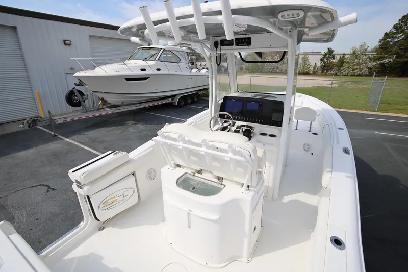 Slide: The Image of 2018 Sea Hunt Gamefish 25 boat interior with console and seating, parked near another boat. - 12