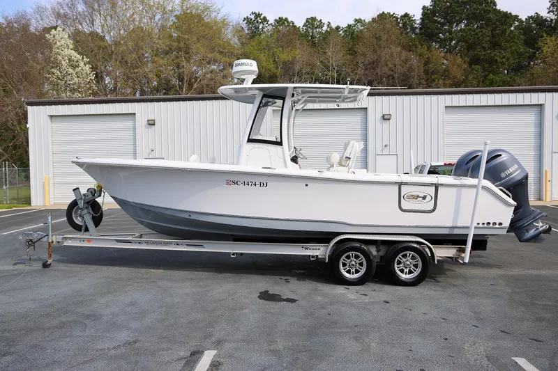 Slide: The Image of 2018 Sea Hunt Gamefish 25 boat on trailer, parked outdoors near a warehouse. - 5