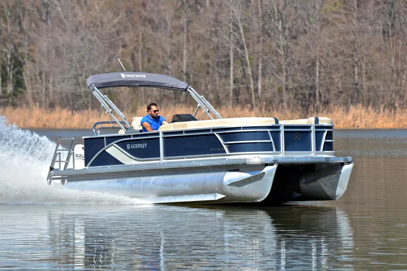 The Image of 2025 Godfrey Sweetwater 2086 C pontoon boat cruising on a calm lake. - 1