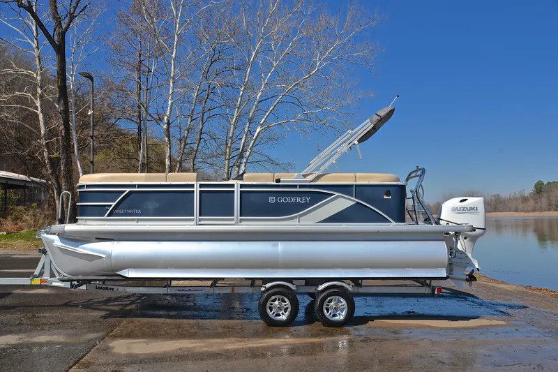 Slide: The Image of 2025 Godfrey Sweetwater 2086 C pontoon boat on trailer by a lake. - 11