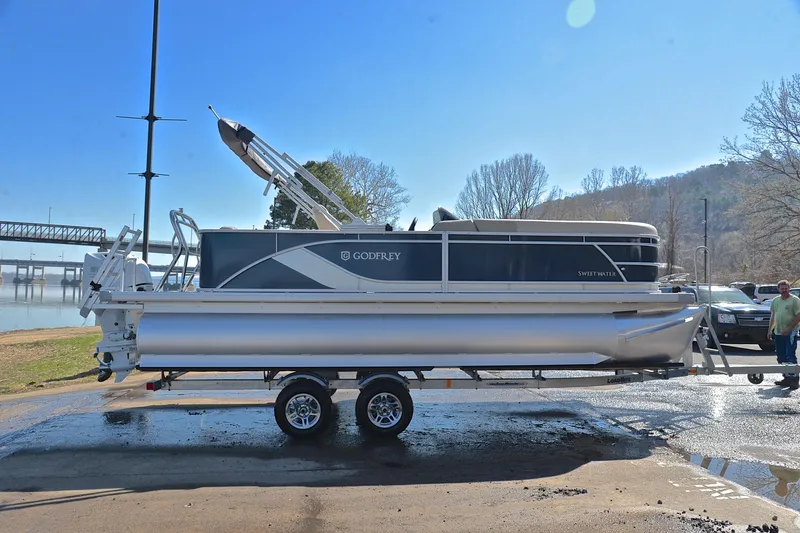 Slide: The Image of 2025 Godfrey Sweetwater 2086 C pontoon boat on trailer by a riverside. - 15