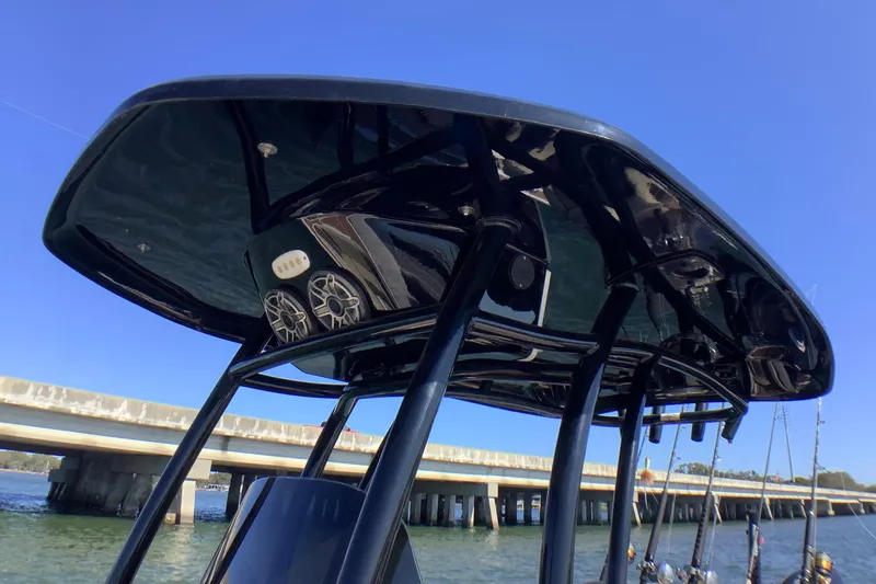 Slide: The Image of 2018 Tidewater 2700 Carolina Bay boat with T-top and speakers, under clear blue sky. - 19