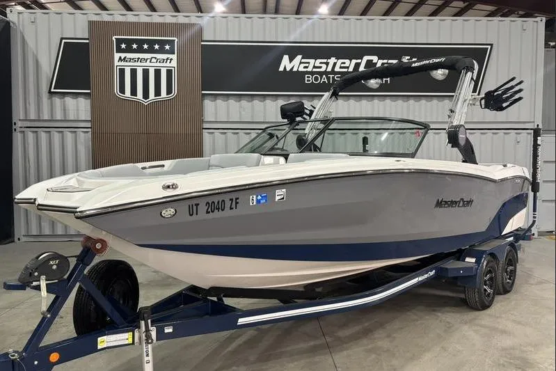 The Image of 2023 MasterCraft NXT24 boat on trailer in showroom setting. - 1