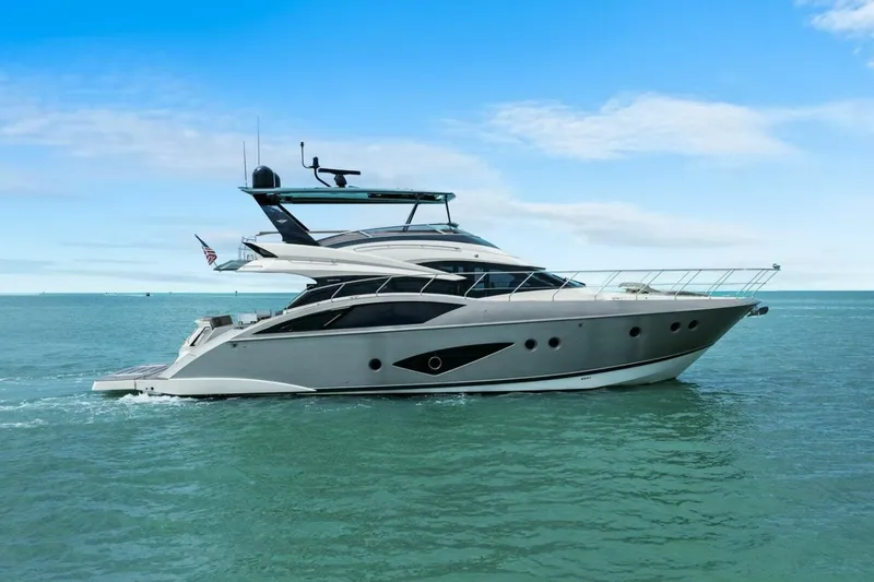 The Image of 2014 Marquis 630 Sport Yacht cruising on open water under a clear blue sky. - 1