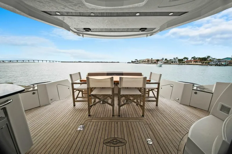 Slide: The Image of Luxurious 2014 Marquis 630 Sport Yacht deck with dining area, overlooking serene waters. - 18